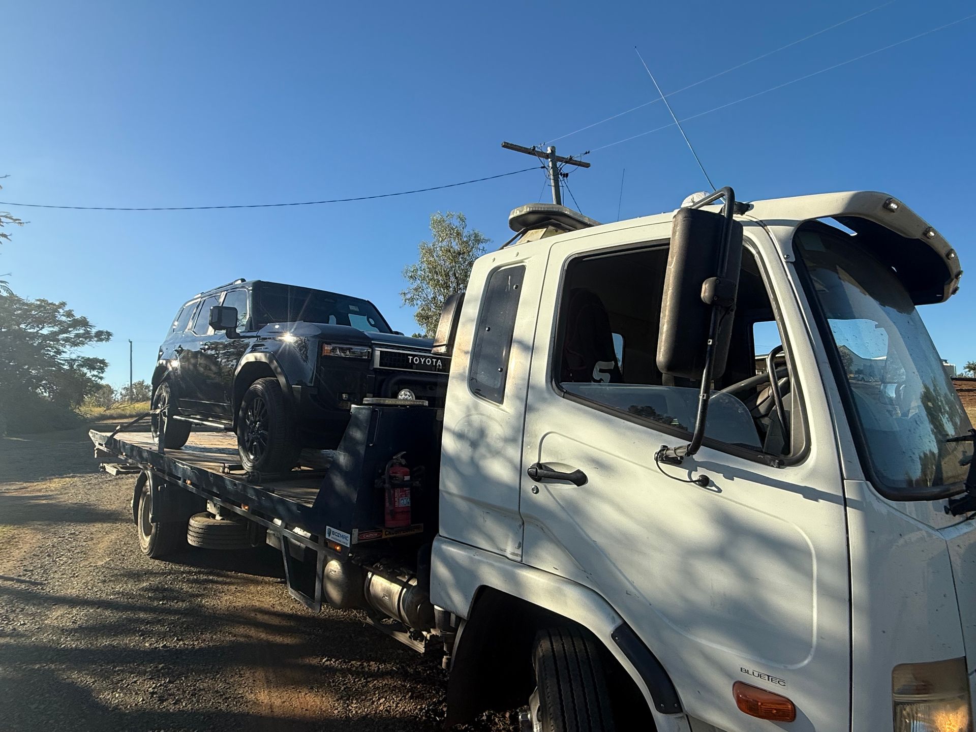 A Tow Truck Is Towing A Small Car On A Highway — Rockhampton Towing And Transport in Gladstone, QLD