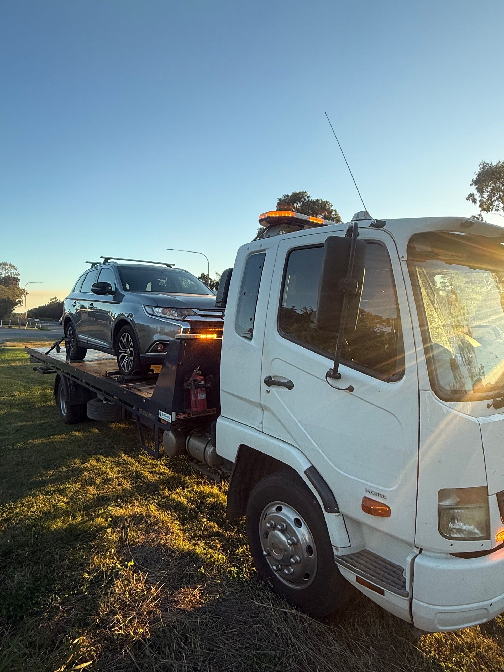 A White Car Is Sitting On Top Of A Tow Truck — Rockhampton Towing And Transport in Gracemere, QLD