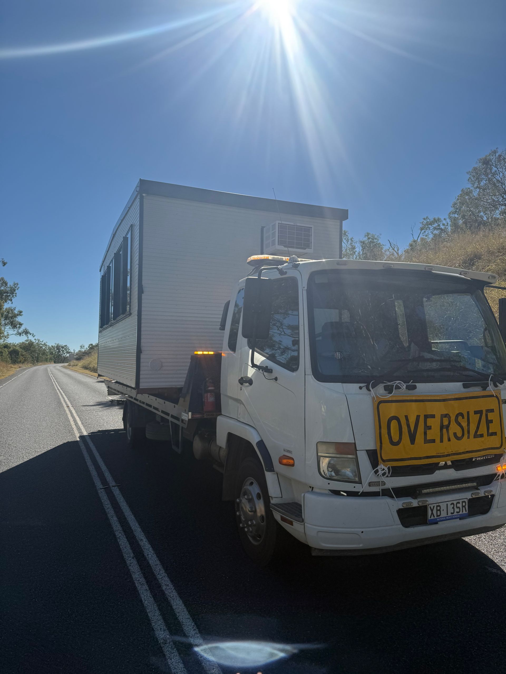 A White Tow Truck Is Carrying A Shipping Container — Rockhampton Towing And Transport in Gracemere, QLD