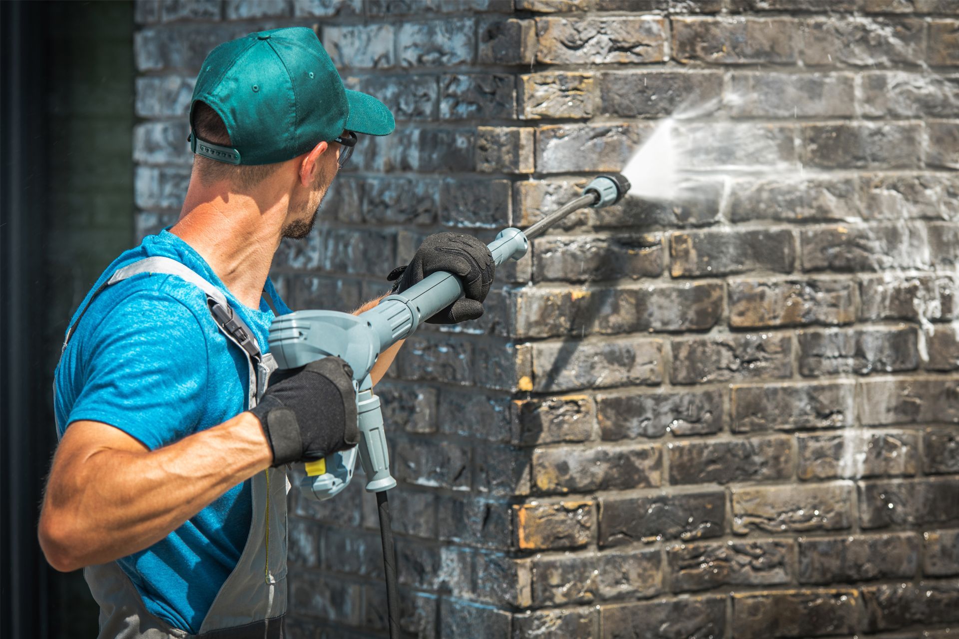 Man power washing a dark brick wall. Man power washing a dark brick wall.