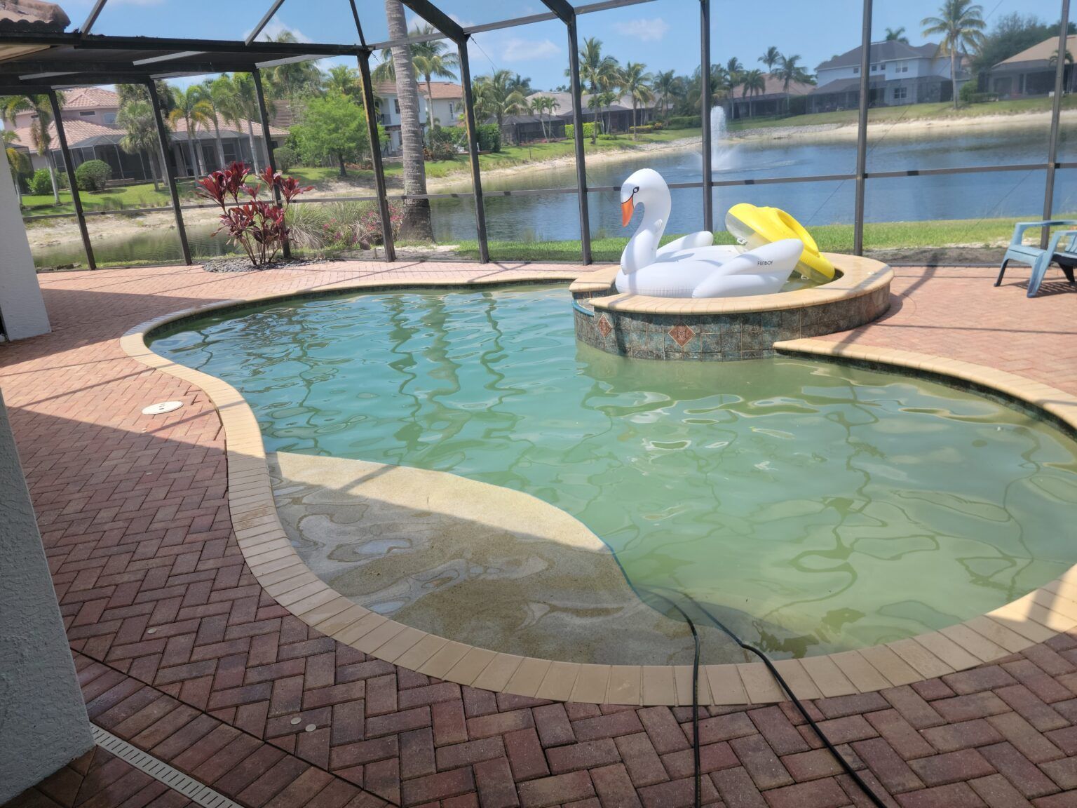Pool with swan float, overlooking lake, red brick patio.