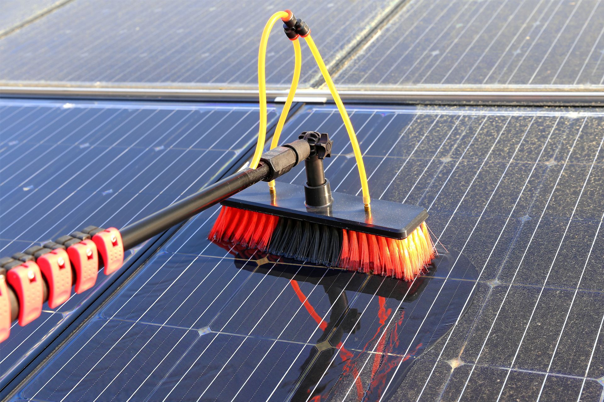 Brush cleaning solar panels on a rooftop.