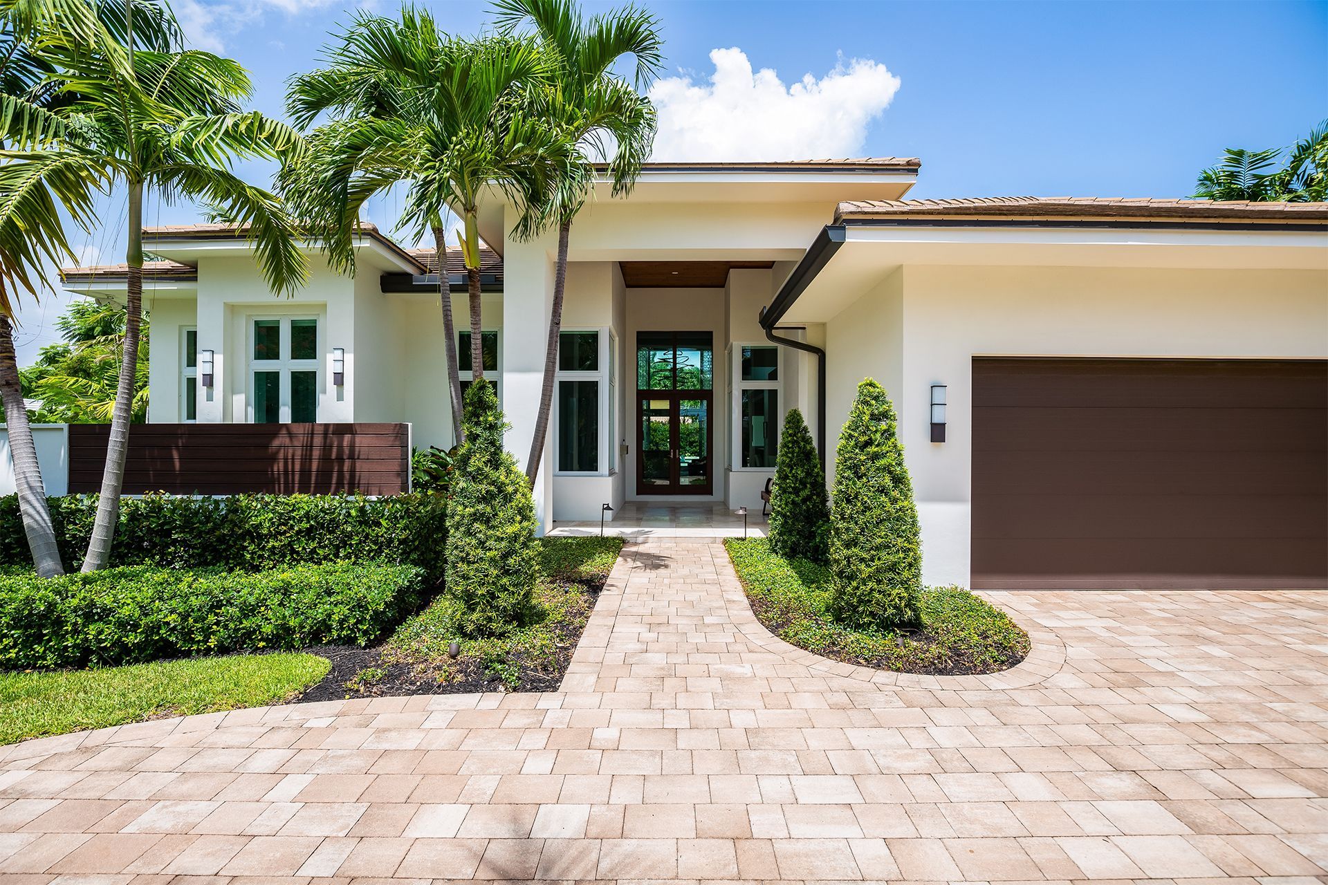 Modern, white home with brown garage door, and brick pathway.