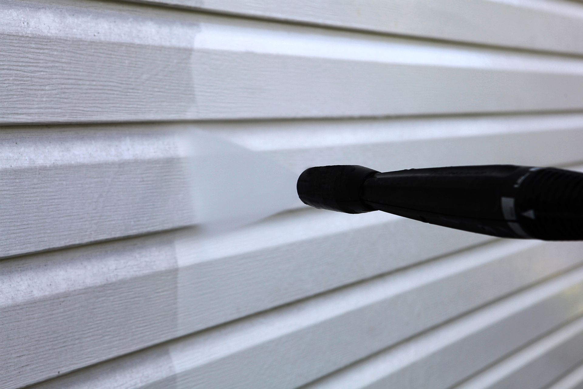 Pressure washing white vinyl siding, revealing a clean strip. Pressure washing white vinyl siding, revealing a clean strip.