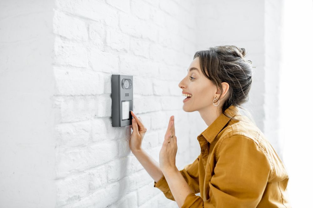 A woman is looking at an intercom on a brick wall.