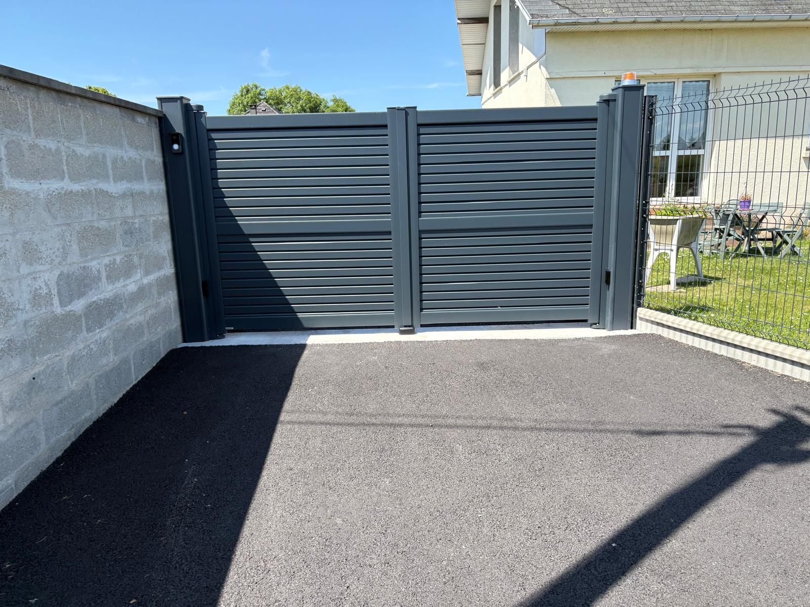 Portail battant en aluminium devant une maison avec moteur