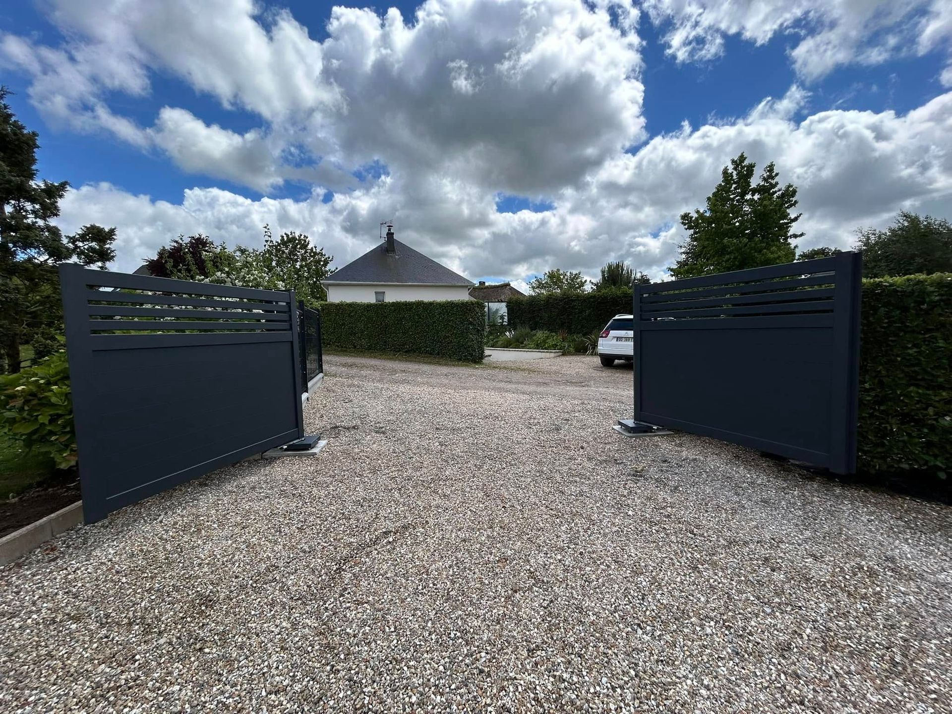 Un portail gris battant ouvert en aluminium