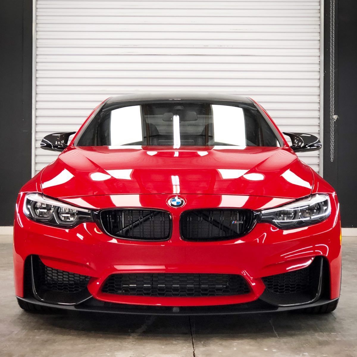 A red bmw is parked in front of a garage door