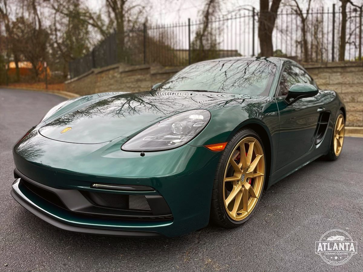 A green sports car with gold wheels is parked in a parking lot.