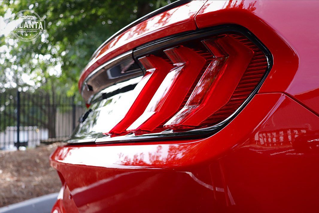 Red car's tail light, showing distinctive three-bar design. Outdoor setting.