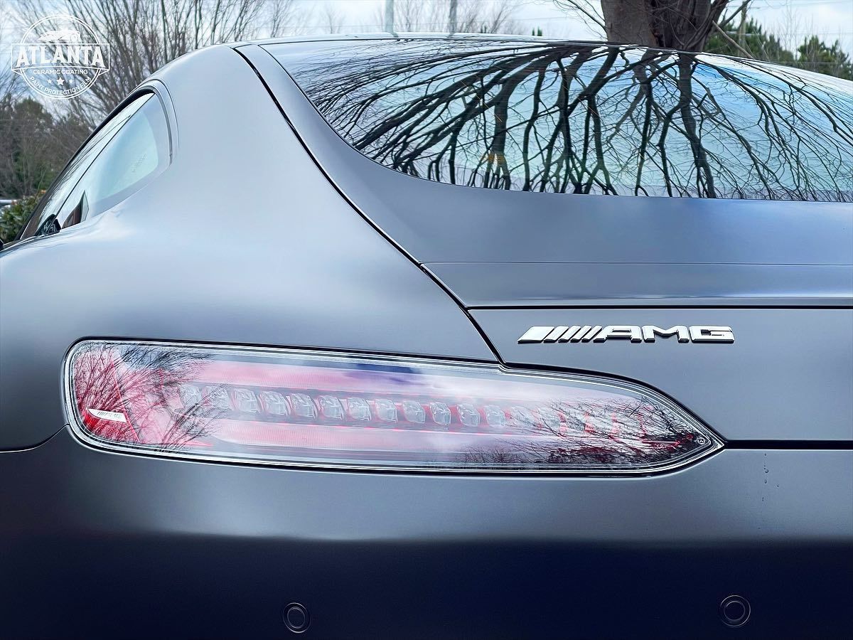 Rear view of a dark gray Mercedes-AMG GT sports car, with taillight detail and AMG emblem.