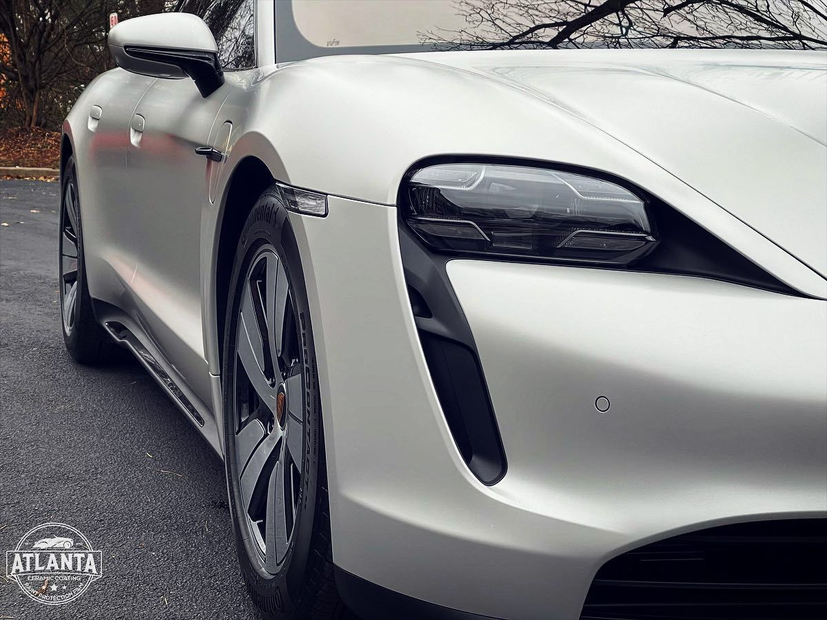 White Porsche Taycan electric vehicle, close-up of the front, on a wet road.