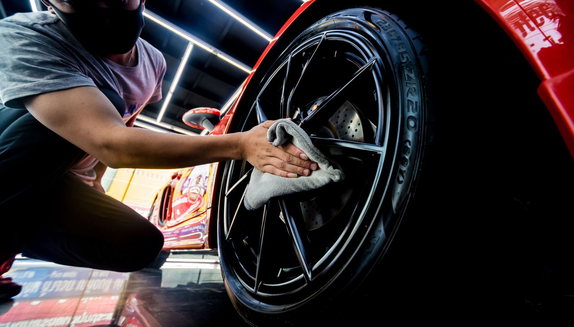 A man is cleaning a car wheel with a cloth.
