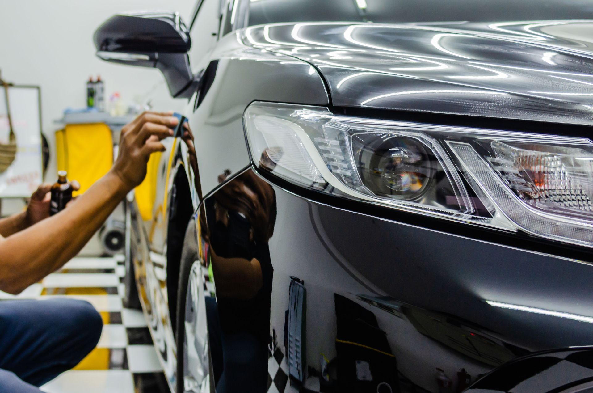 A man is polishing a car in a garage.