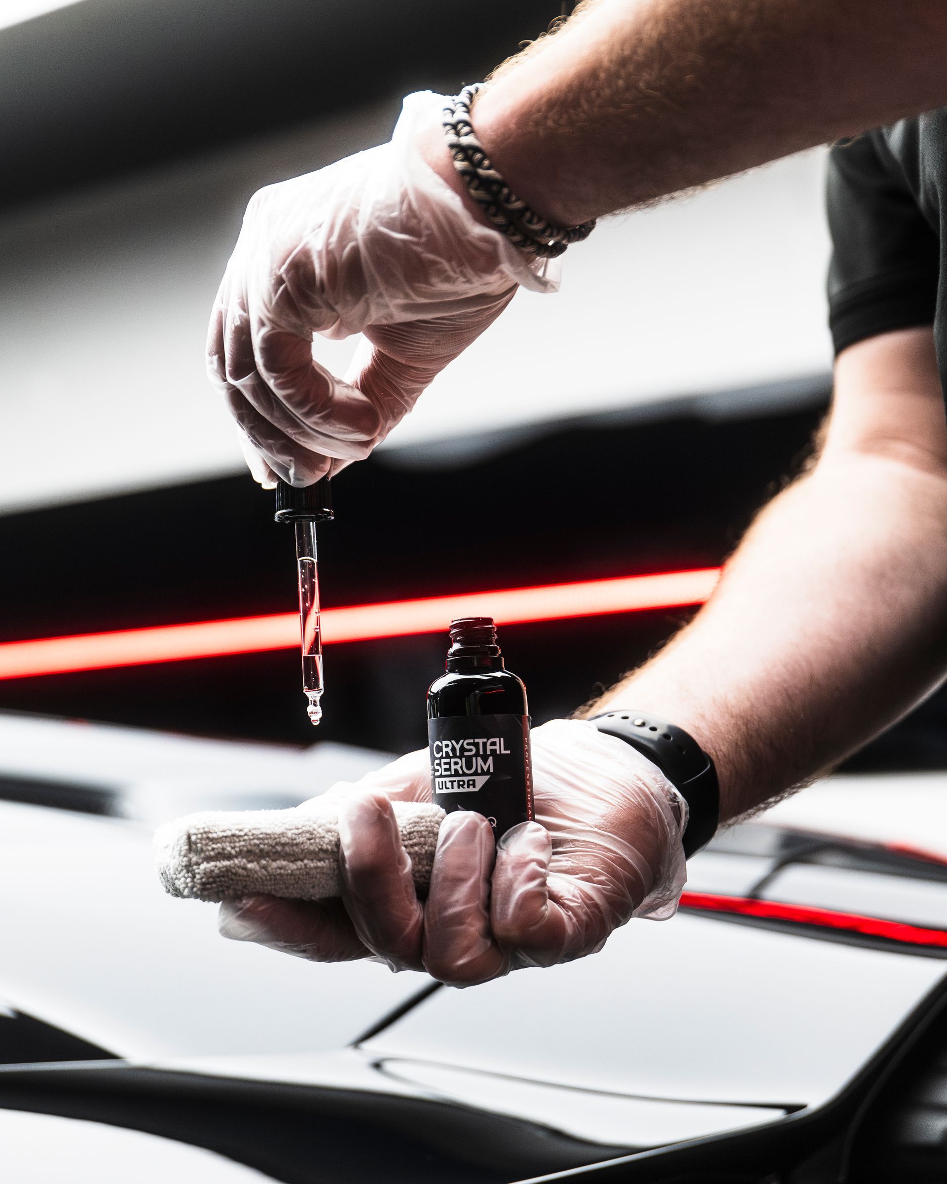 A man wearing gloves is holding a bottle of liquid in his hand.