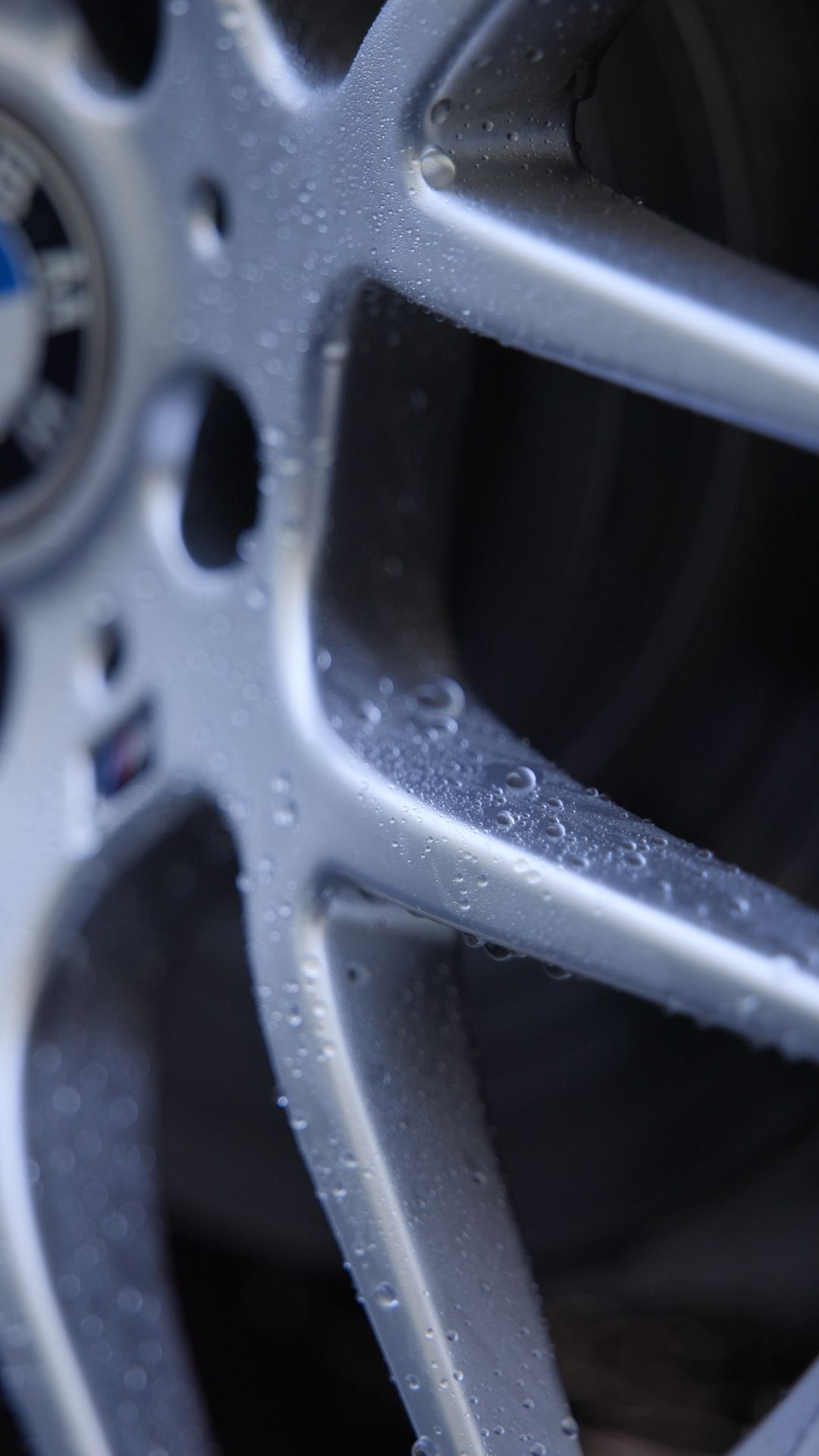 A close up of a car wheel with water drops on it.