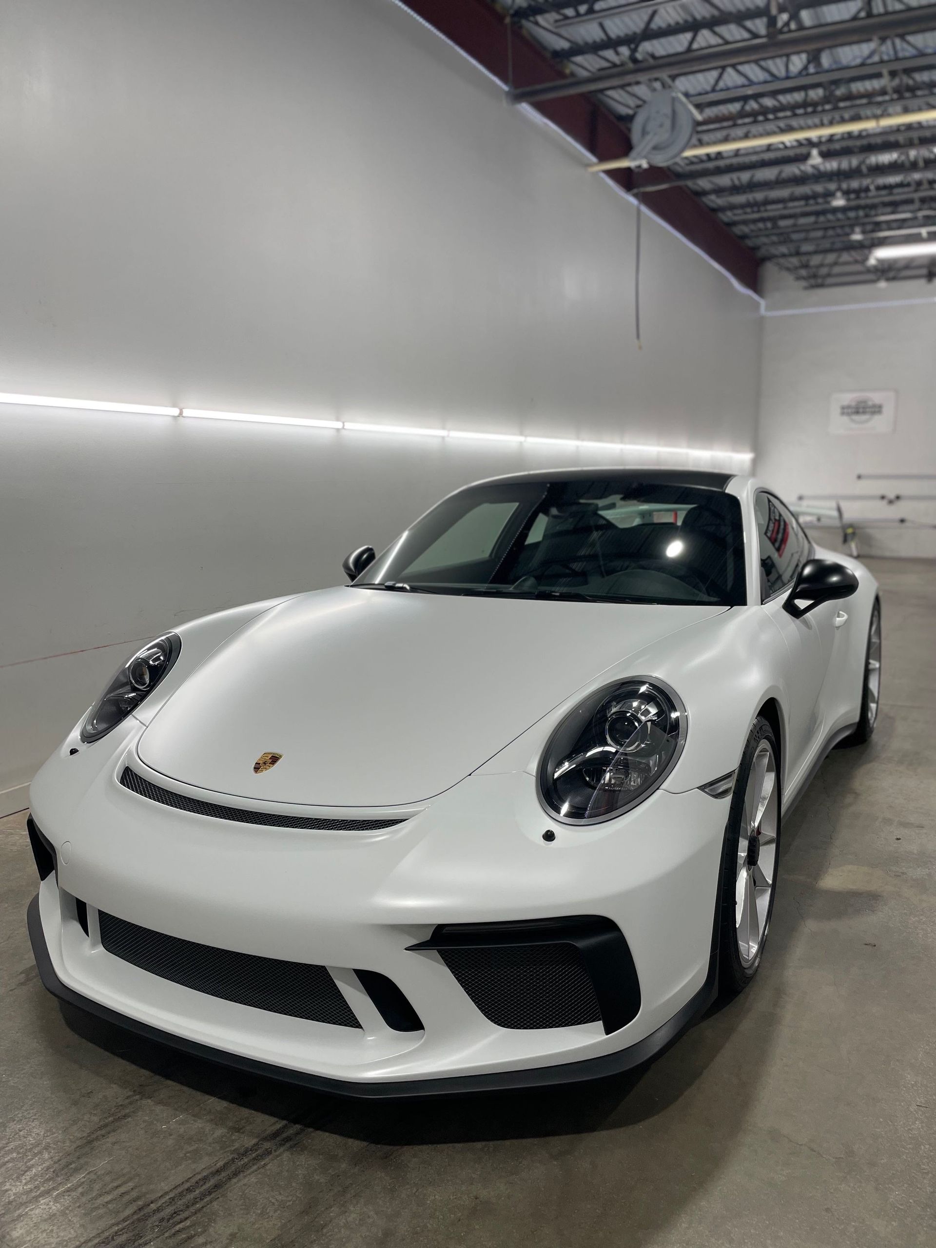 A white porsche 911 gt3 is parked in a garage.