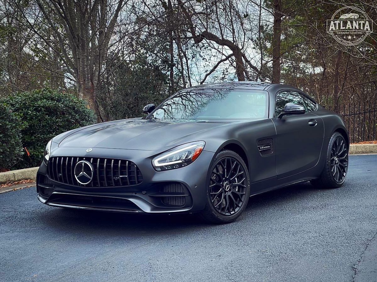 A black mercedes amg gt is parked on the side of a road.