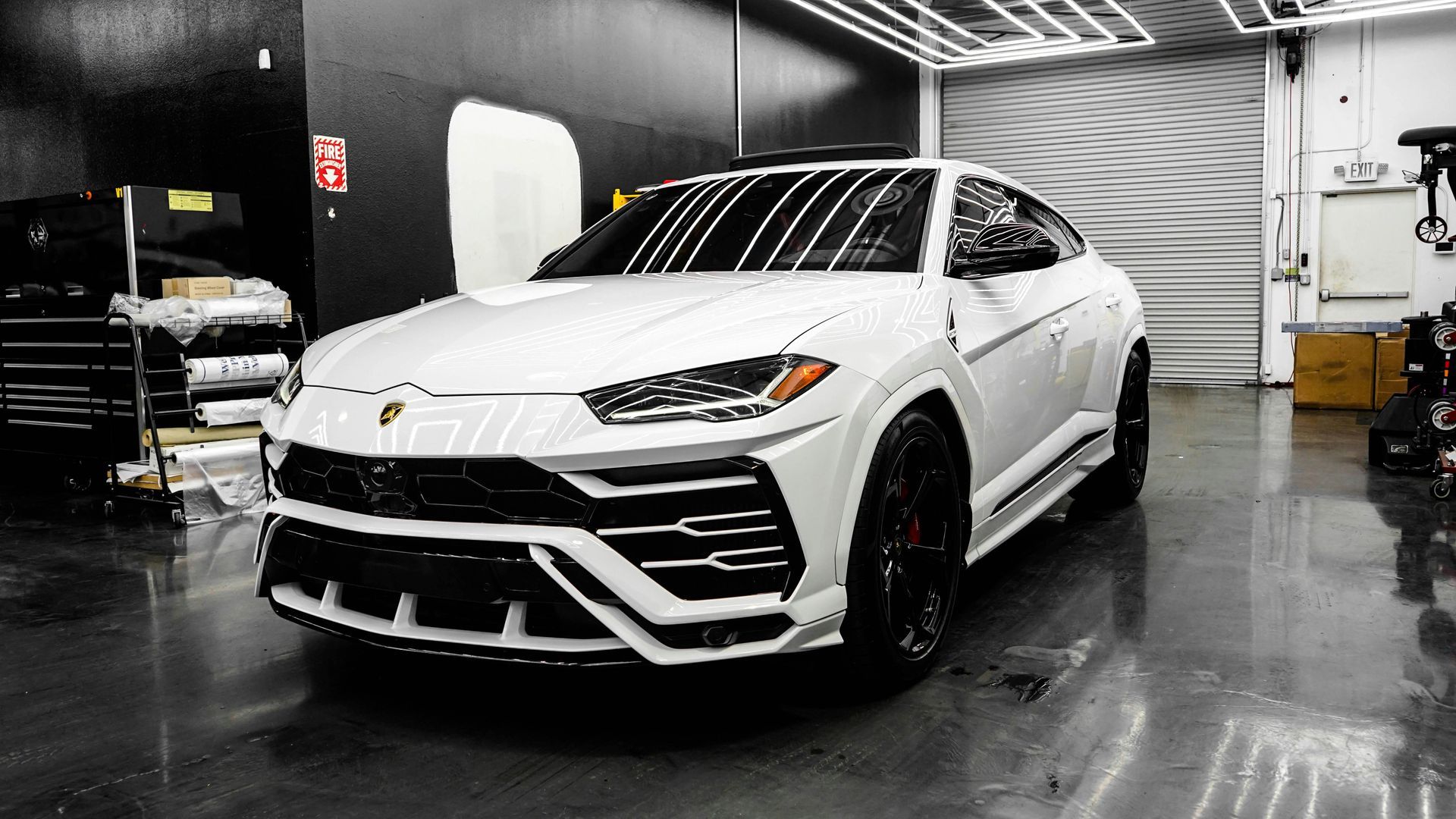 A white lamborghini urus is parked in a garage.