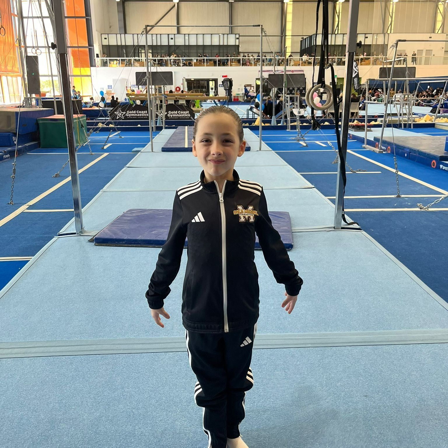 Young Gymnast in Black Tracksuit Smiling in a Gymnastics Gym — Gold Medal Gymnastics In Molendinar, QLD