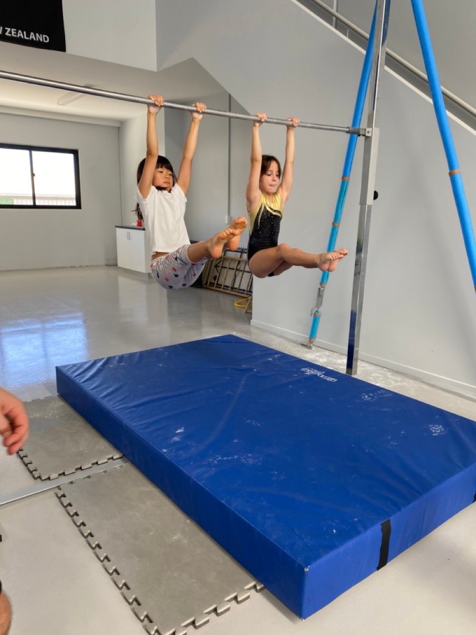 A Boy And A Girl Are Hanging From A Bar In A Gym — Gold Medal Gymnastics In Gold Coast, QLD