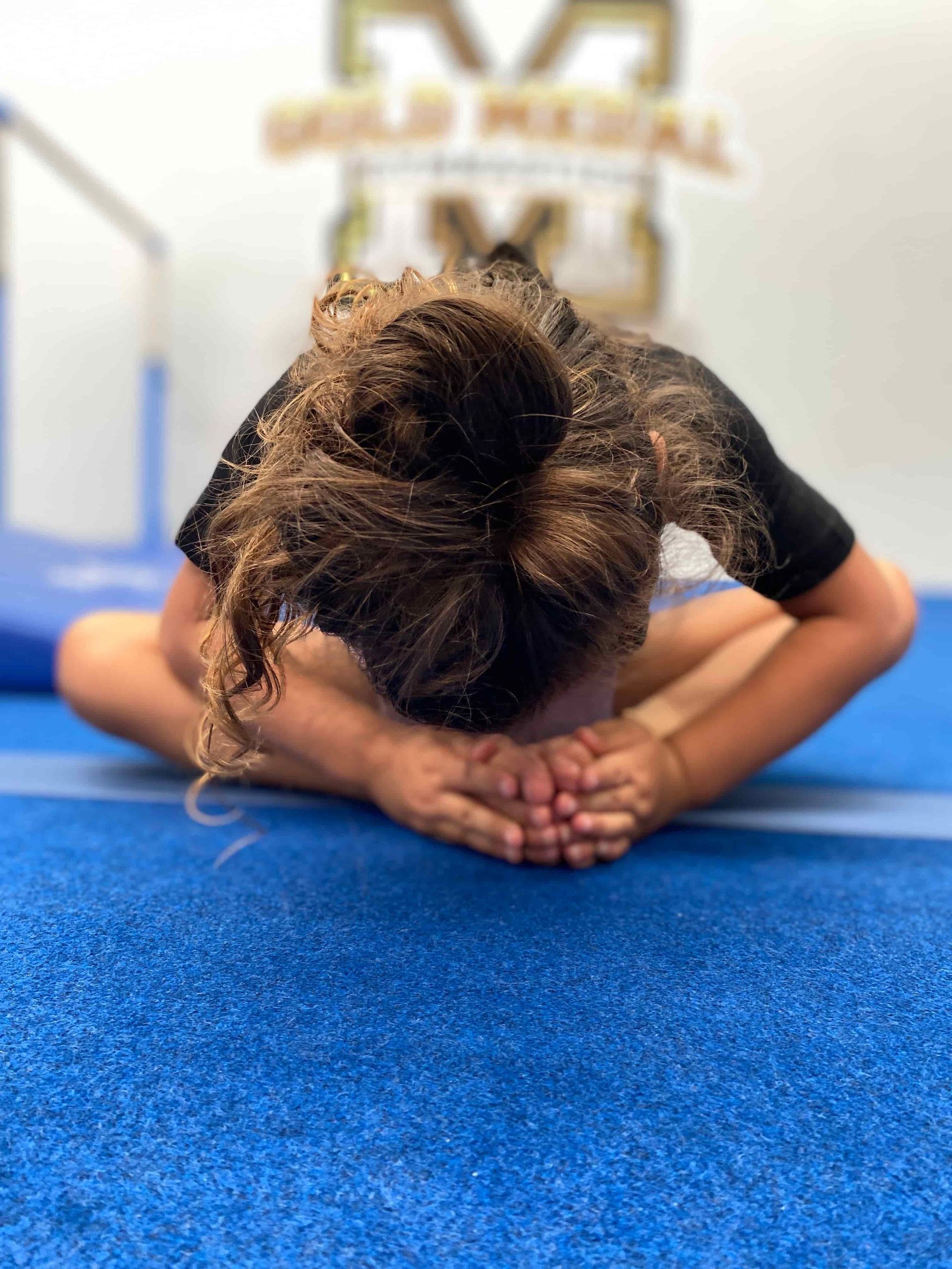 A girl is sitting on the floor with her head down — Gold Medal Gymnastics In Molendinar, QLD