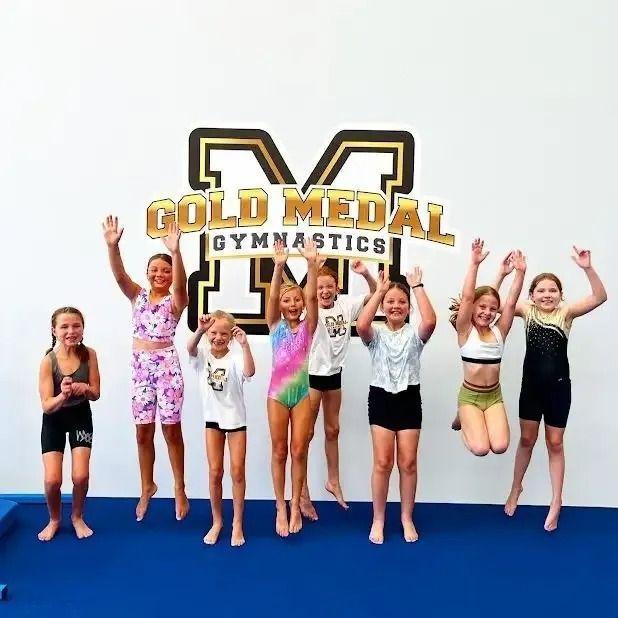Young Girls Are Jumping In The Air In Front Of A Gold Medal Gymnastics — Gold Medal Gymnastics In Gold Coast, QLD