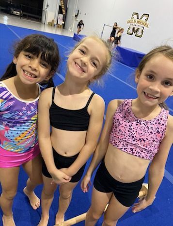 Three Young Girls Are Posing For A Picture In A Gym — Gold Medal Gymnastics In Molendinar, QLD