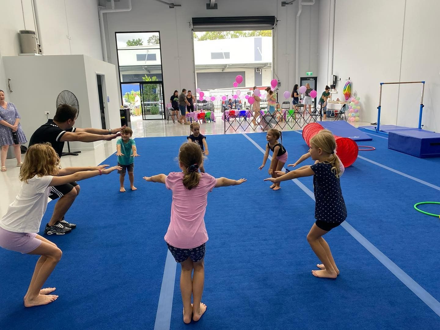 A Group Of Children Are Doing Exercises On A Blue Mat In A Gym — Gold Medal Gymnastics In Molendinar, QLD