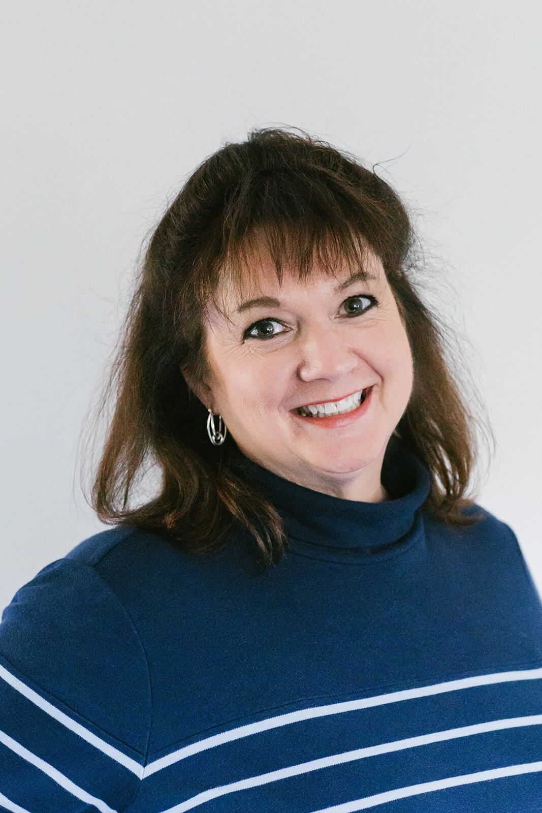 A woman in a blue and white striped sweater is smiling for the camera.