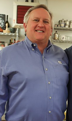 A man in a blue shirt is smiling for the camera