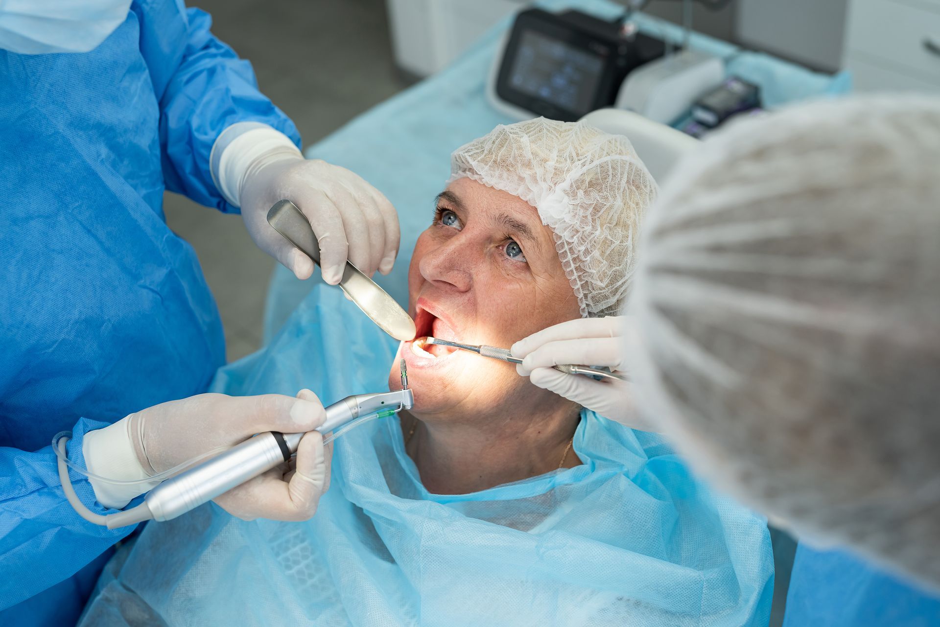 A dentist wearing yellow gloves is pointing at a computer screen