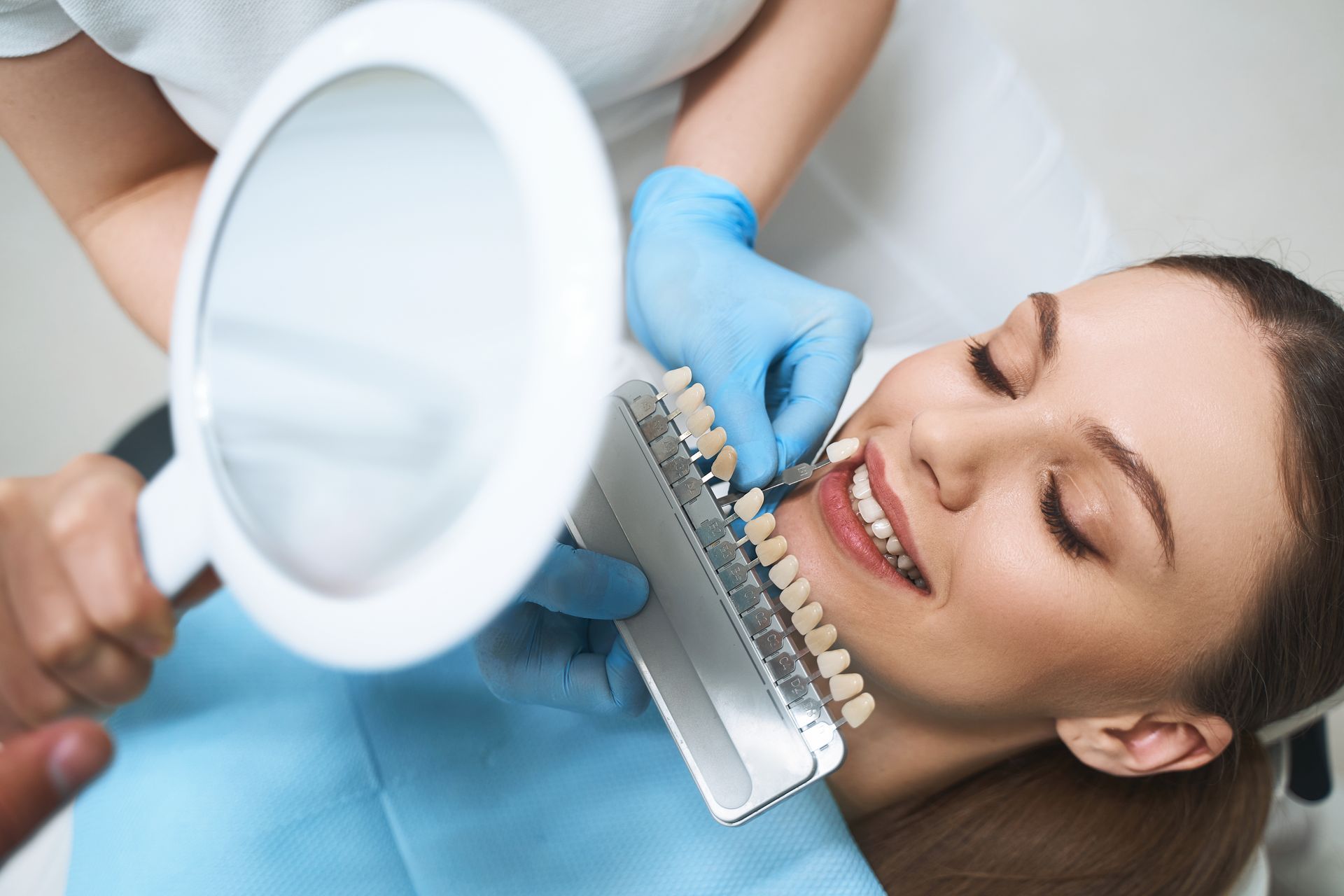 A dentist wearing yellow gloves is pointing at a computer screen