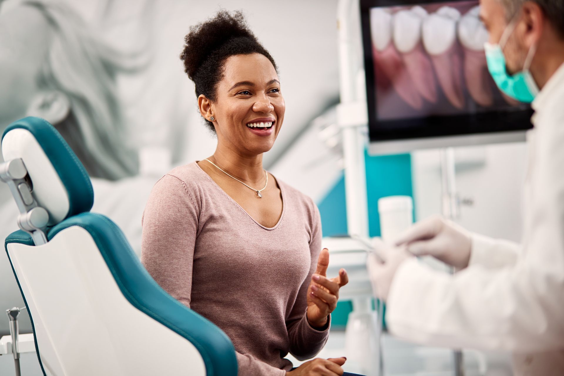 Woman in dental chair smiling at dentist in white coat.