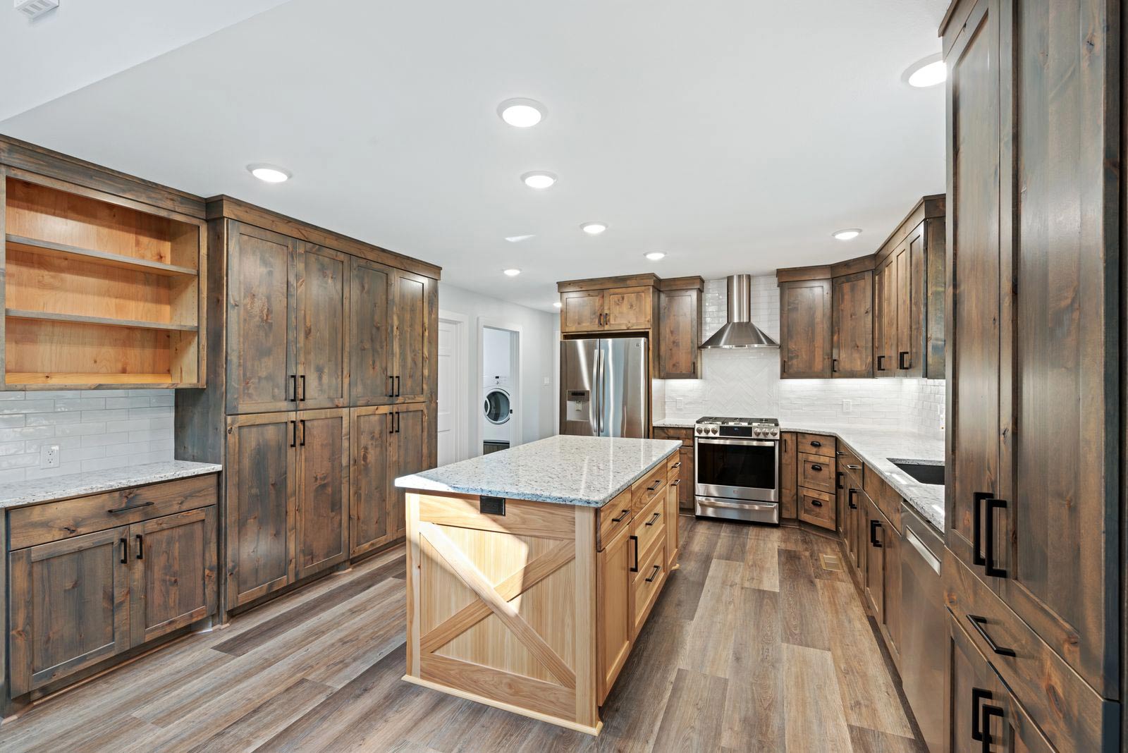 A kitchen with wooden cabinets , granite counter tops , stainless steel appliances and a large island.