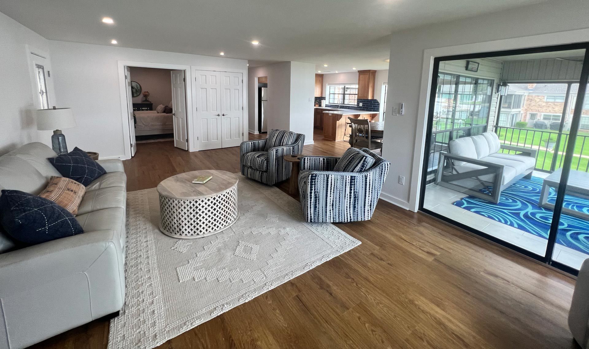 A living room with a couch , chairs , coffee table and sliding glass doors.