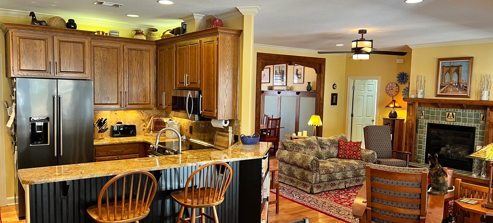 A kitchen and living room in a house with a ceiling fan.