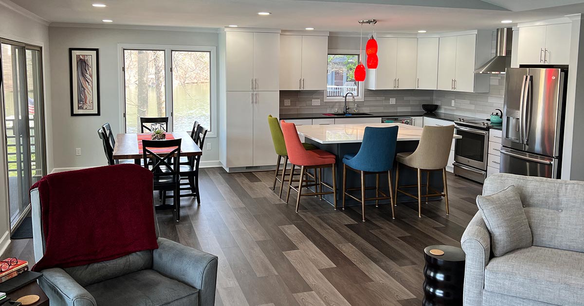 A living room filled with furniture and a kitchen with a table and chairs.