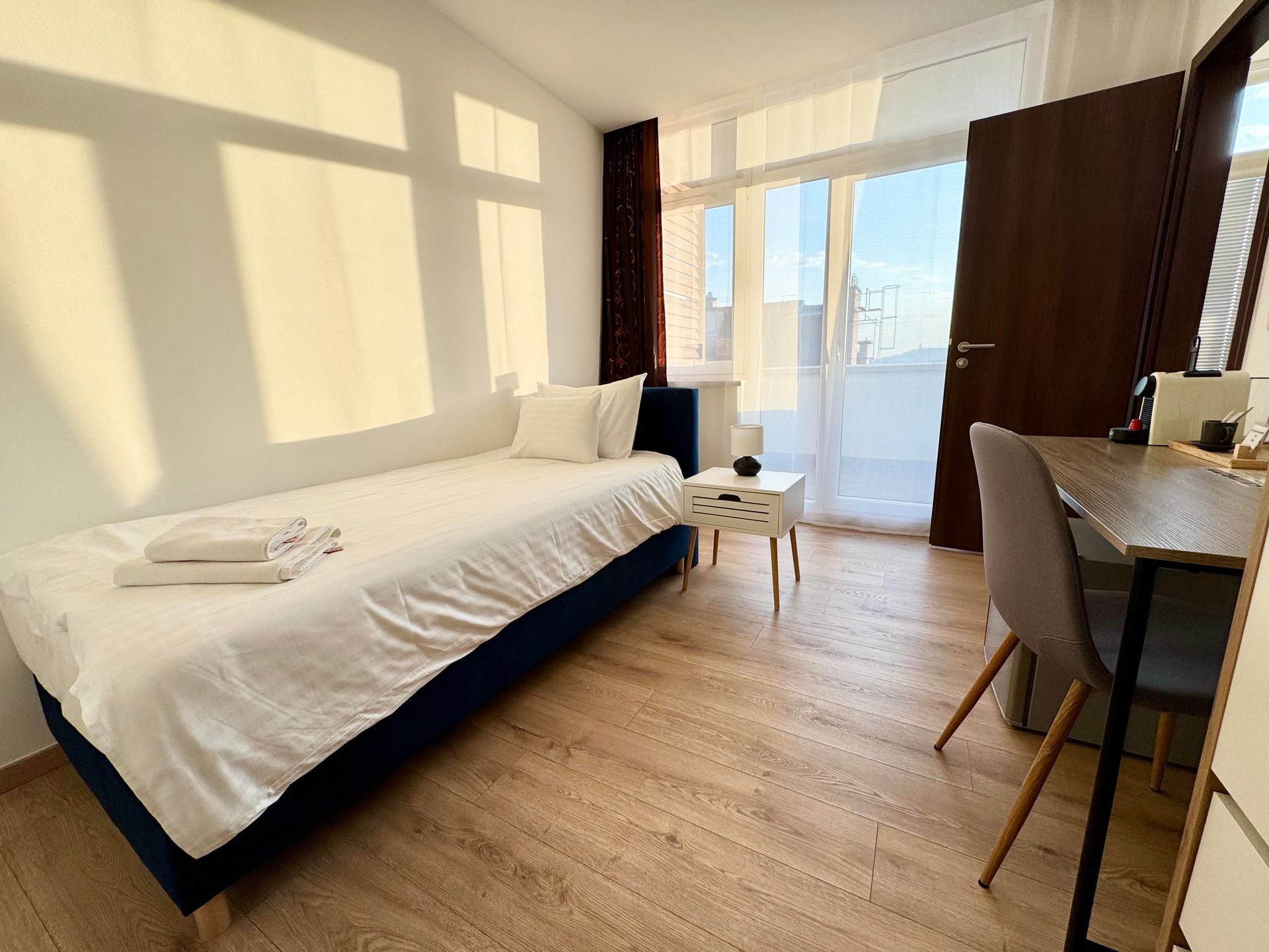 A bedroom with a single bed , desk and chair.