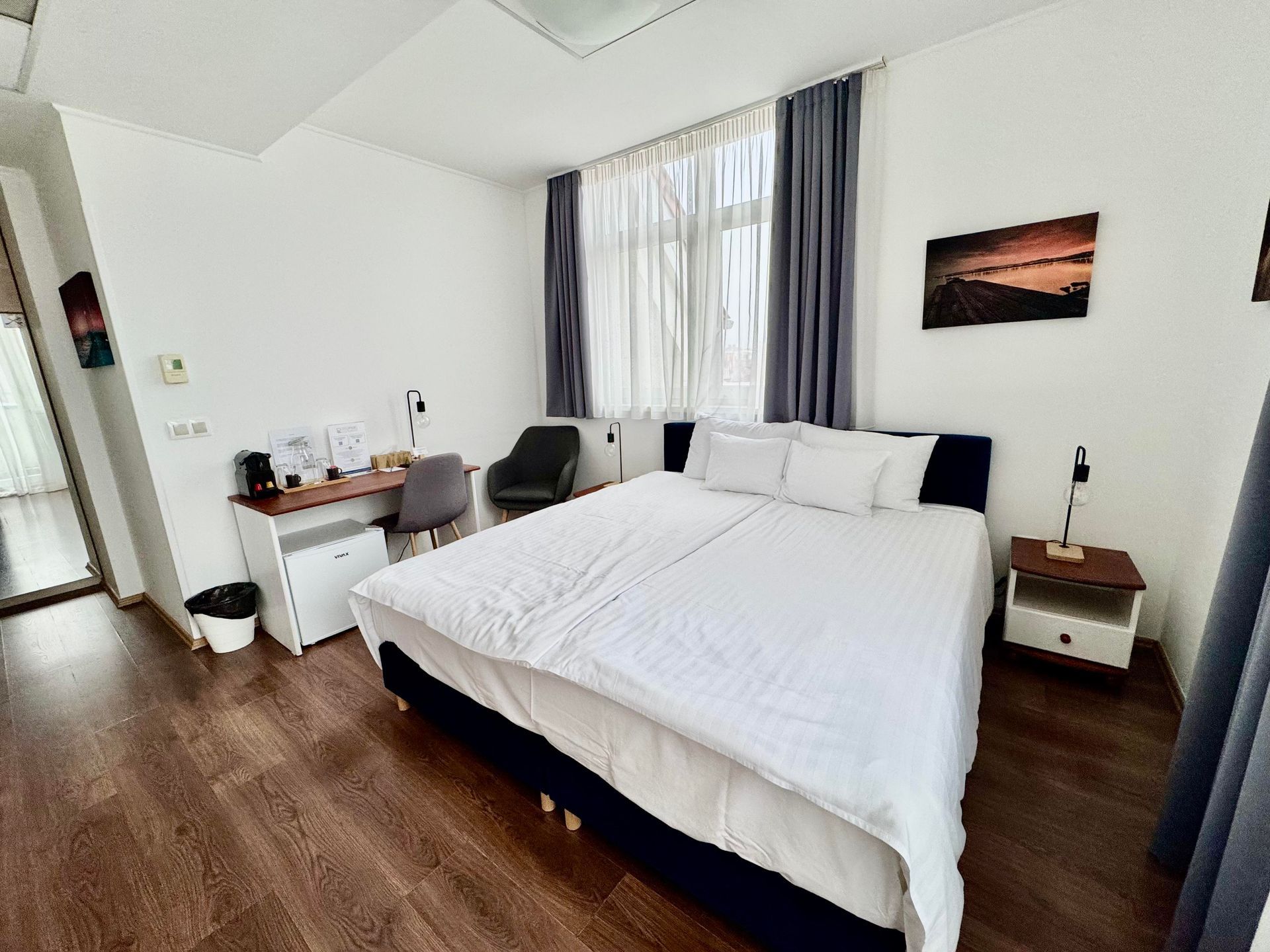 A hotel room with a large bed and a desk.