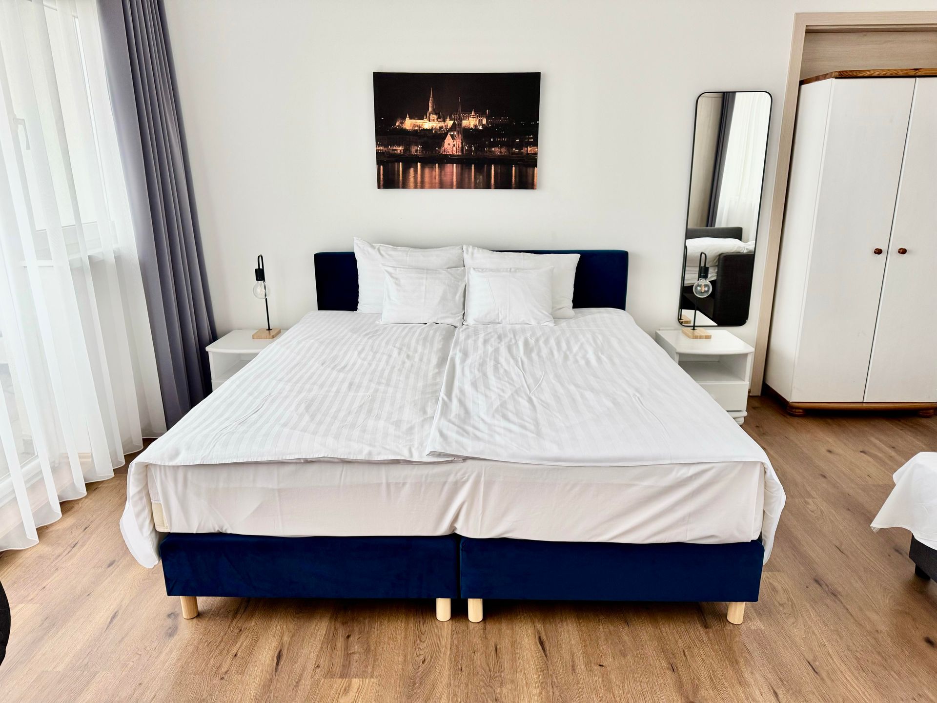 A hotel room with a large bed and a picture on the wall above it