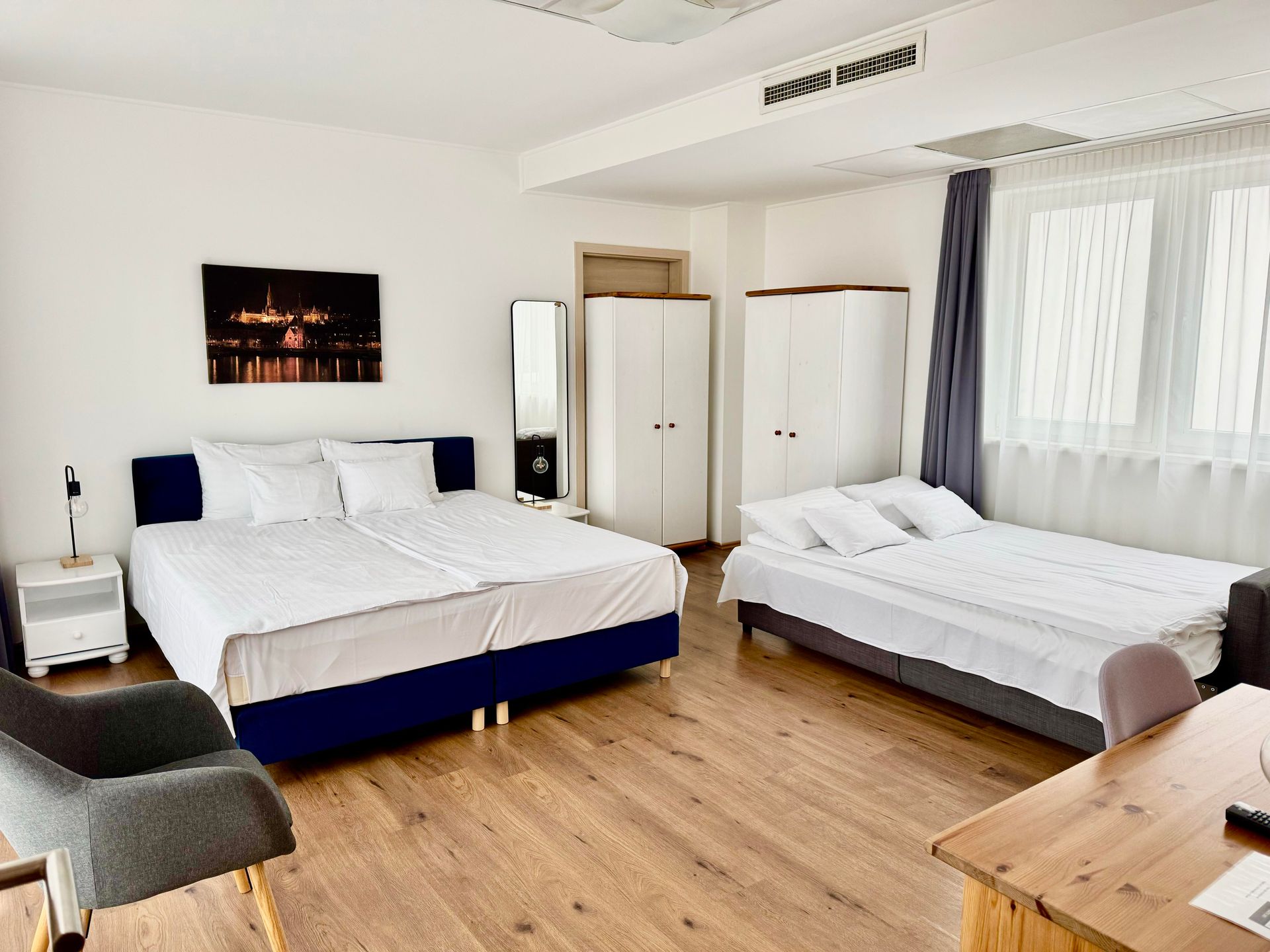 A hotel room with three beds , a desk and a chair.