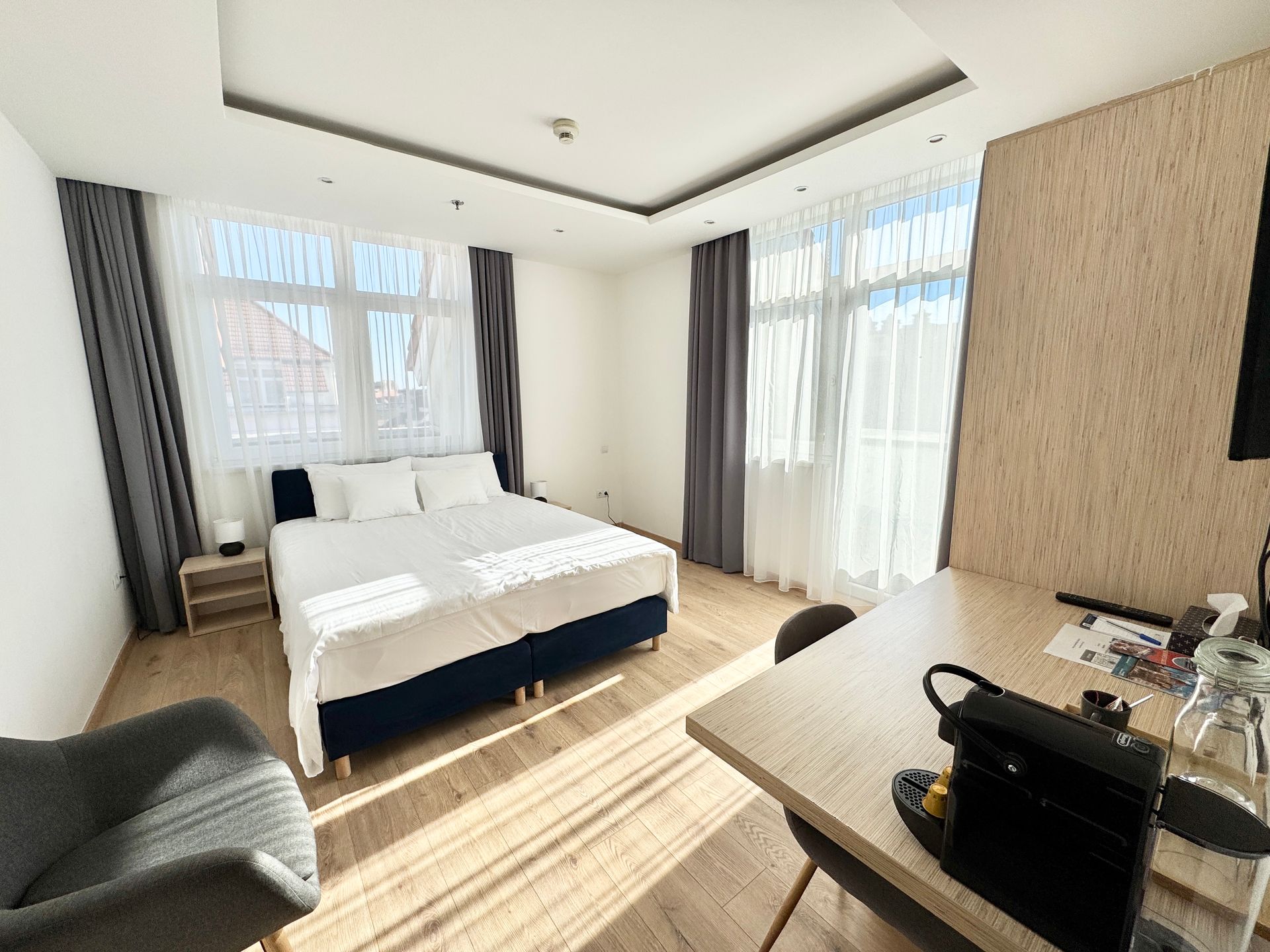 A bedroom with a bed , nightstand , and two windows.