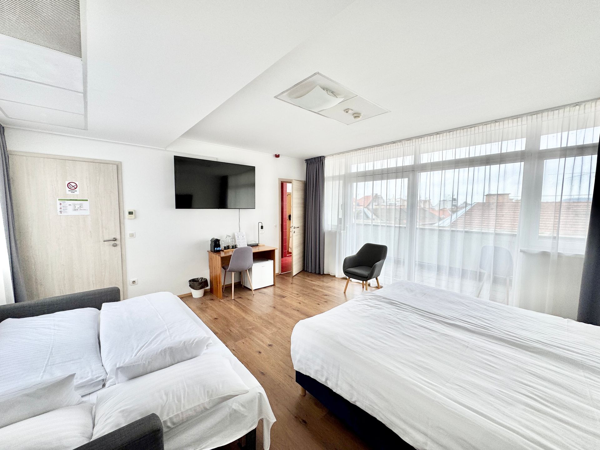 A hotel room with two beds , a couch , a desk and a television.