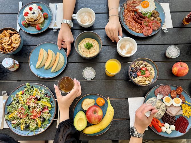 A group of people are sitting at a table eating a variety of food.