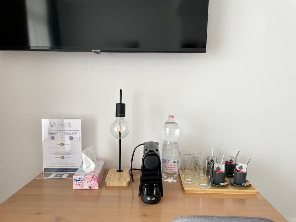 A wooden table with a coffee maker , a lamp , a bottle of water and a flat screen tv.