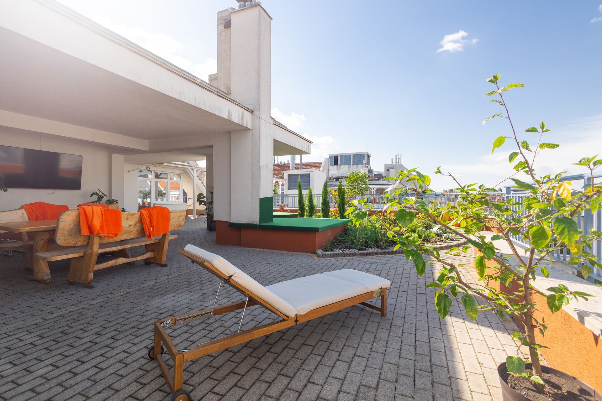 A wooden lounge chair is sitting on a brick patio next to a tree.