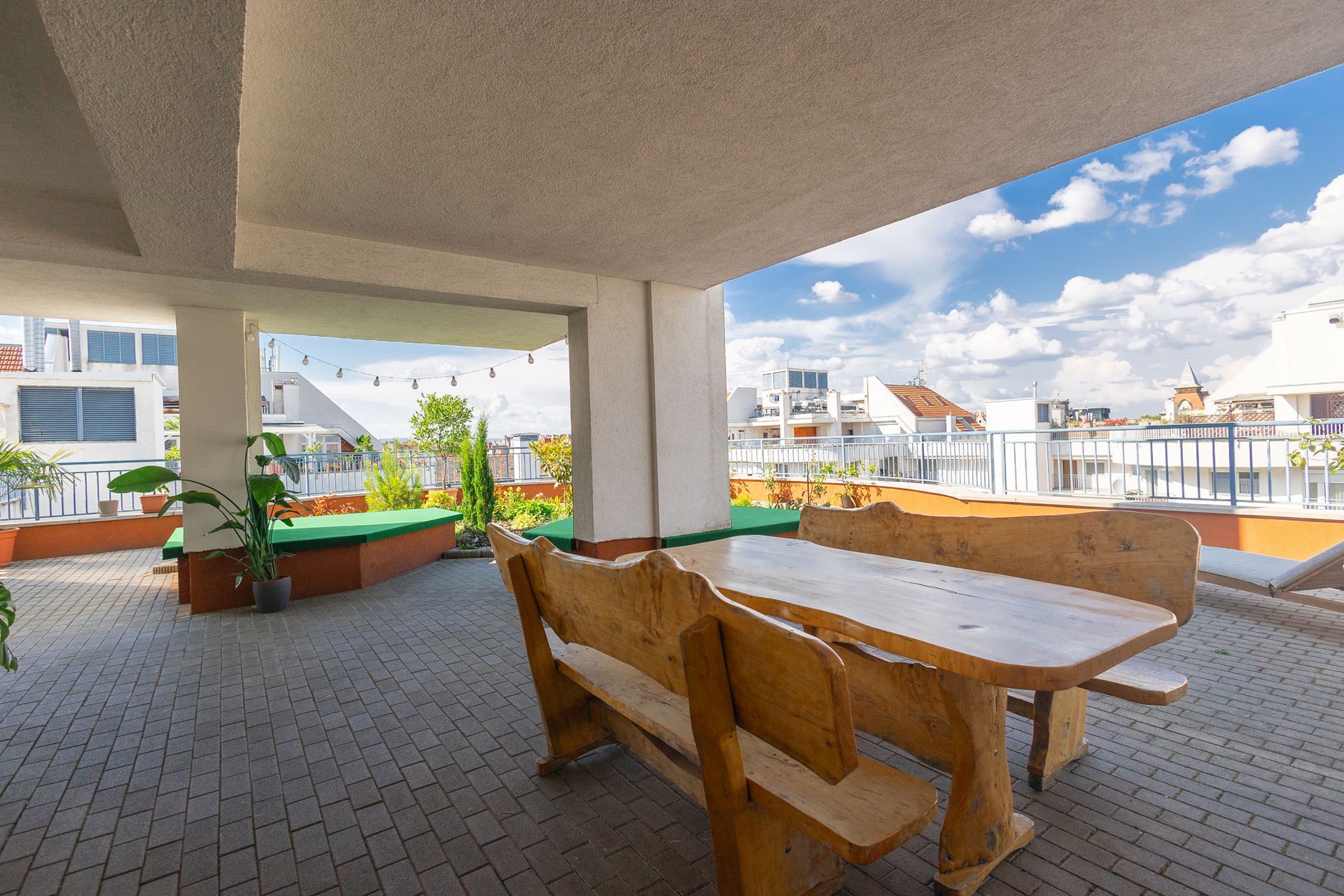 A wooden table and bench on a patio with a view of a city.