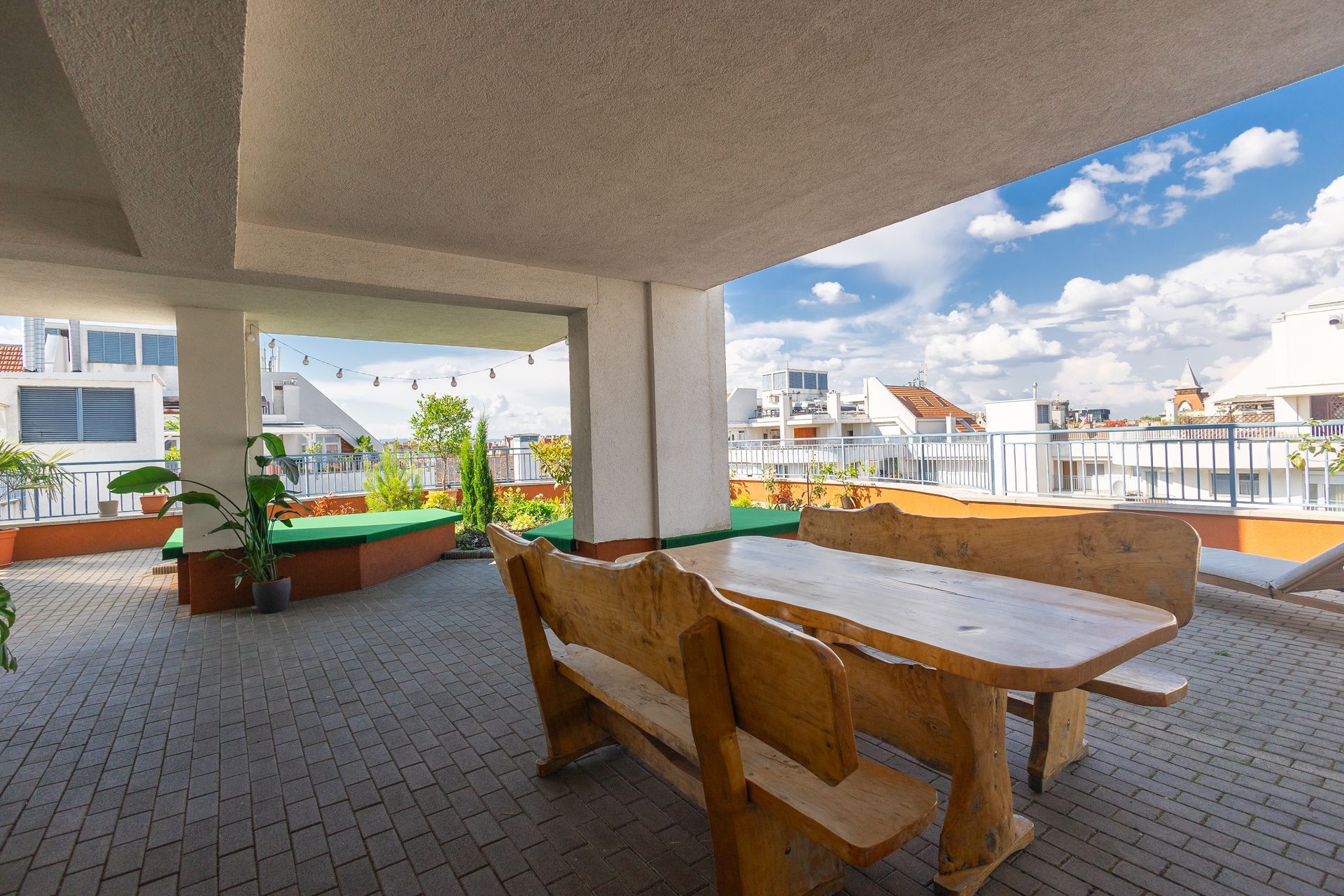 A wooden table and benches on a patio with a view of a city.