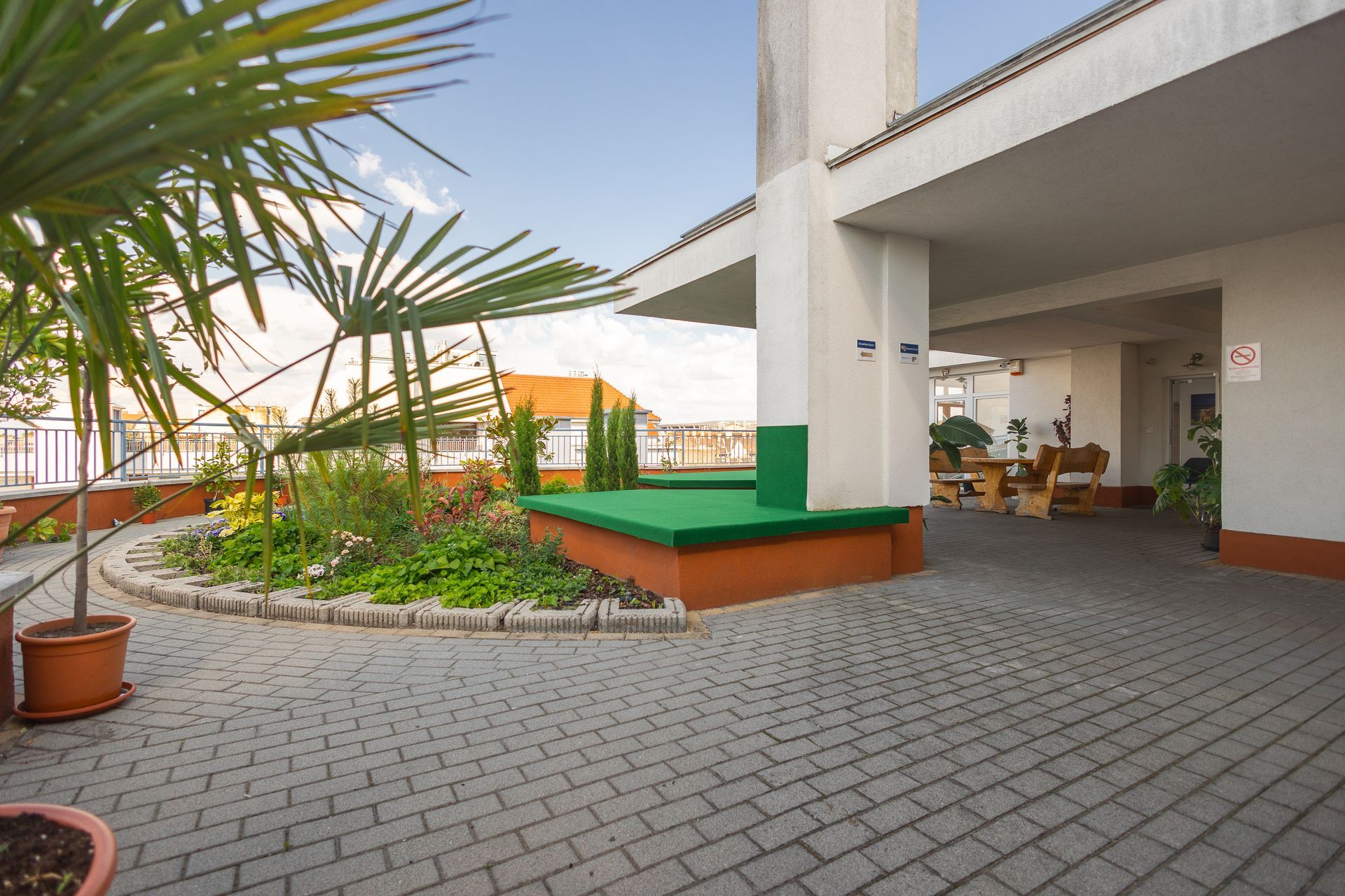 A brick walkway with a green bench in the middle